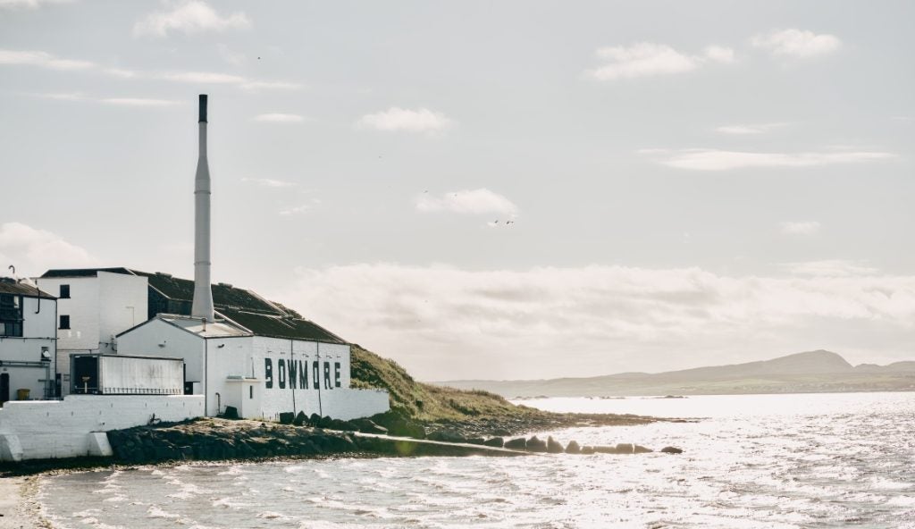 A white-washed distillery in Scotland on the edge of a bay