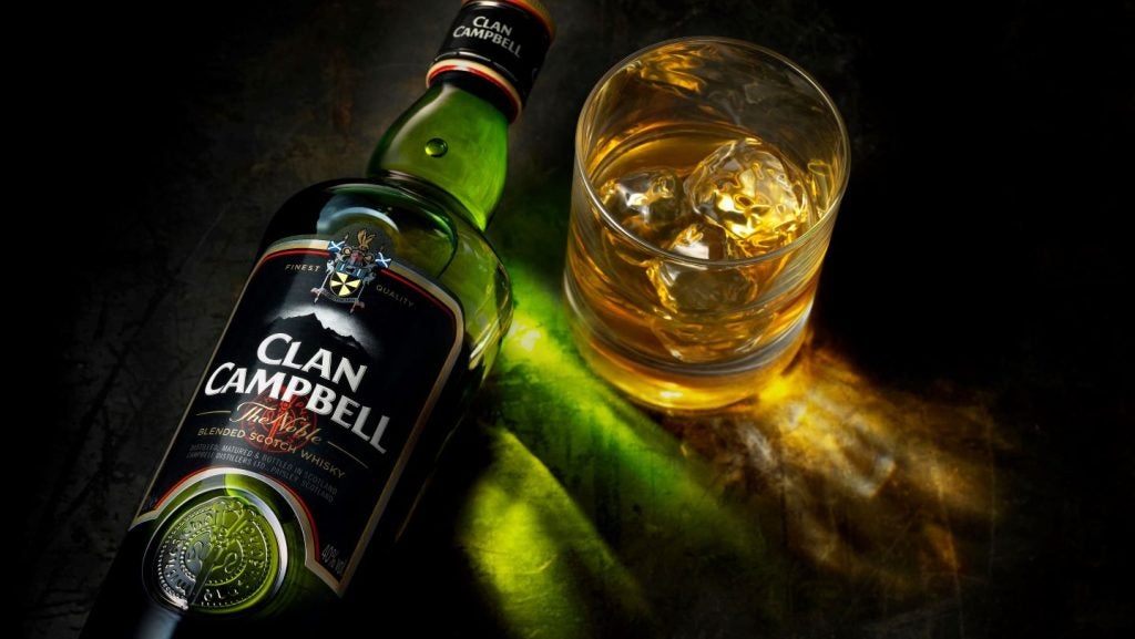 Clan Campbell green bottle, black label on dark background with tumbler glass of Scotch whisky.