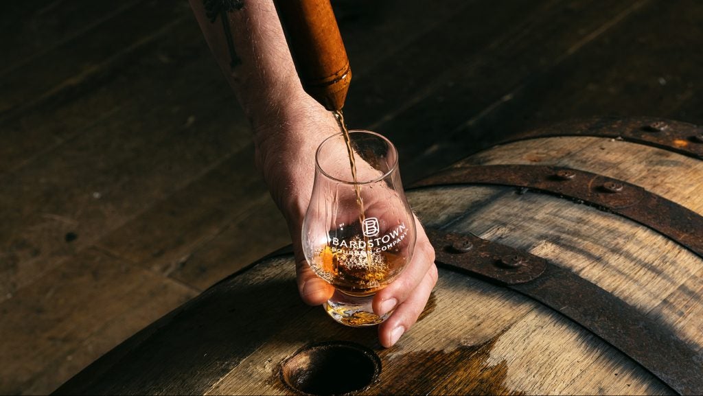 Whiskey being poured into a Bardstown Bourbon Co.-branded glass